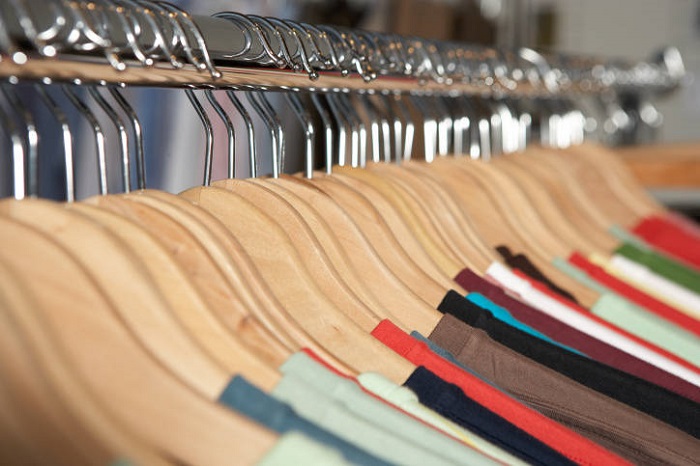 Shirts on wooden hangers on clothes rack (focus on hangers)